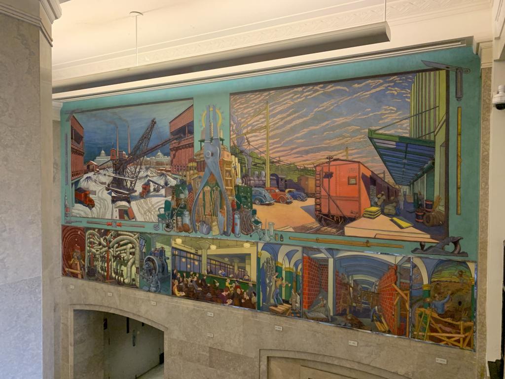 Mural of a fuel depot and supply station above seven smaller paintings showing the activities of the Procurement Division