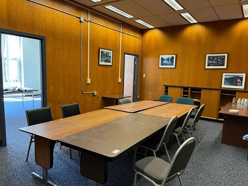 View of a wood paneled conference room with a desk, tables, and 9 chairs.