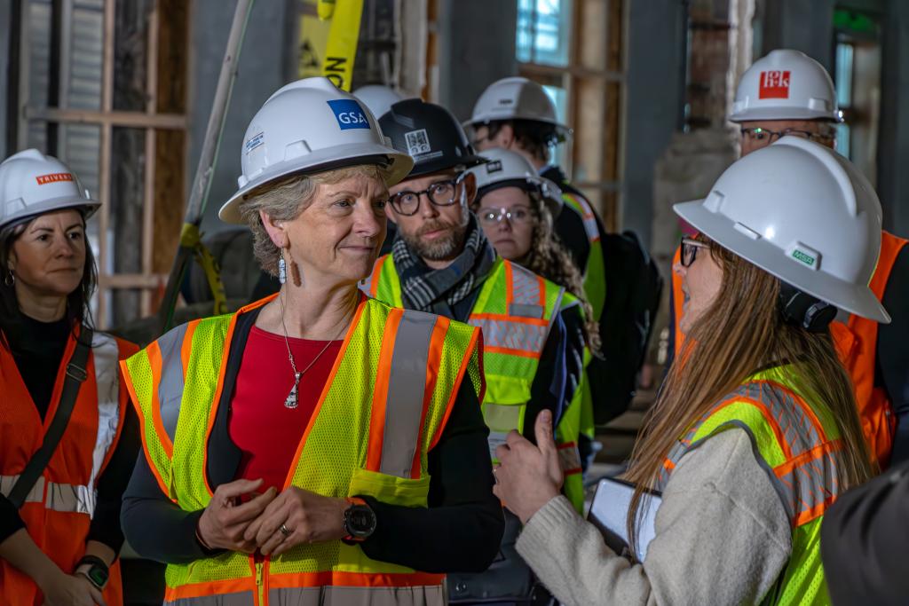 GSA Administrator Robin Carnahan (left) gets briefed on the Moss Modernization project by Erin Holcombe. Both are wearing white hard hats.