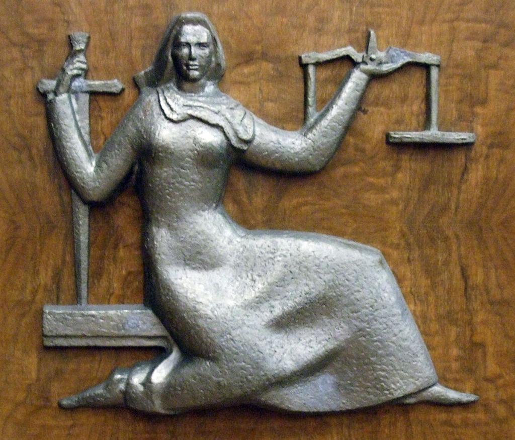 Bas-relief metal sculpture of a woman in a robe carrying scales and a sword