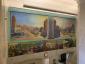 mural of two cityscapes side by side with a row of seven smaller paintings below