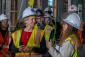 GSA Administrator Robin Carnahan (left) gets briefed on the Moss Modernization project by Erin Holcombe. Both are wearing white hard hats.