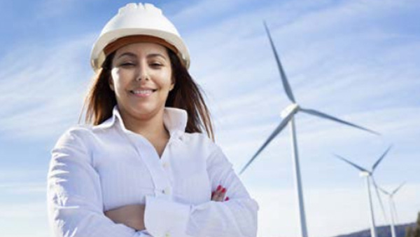 Woman in energy company uniform standing in front of windmills.